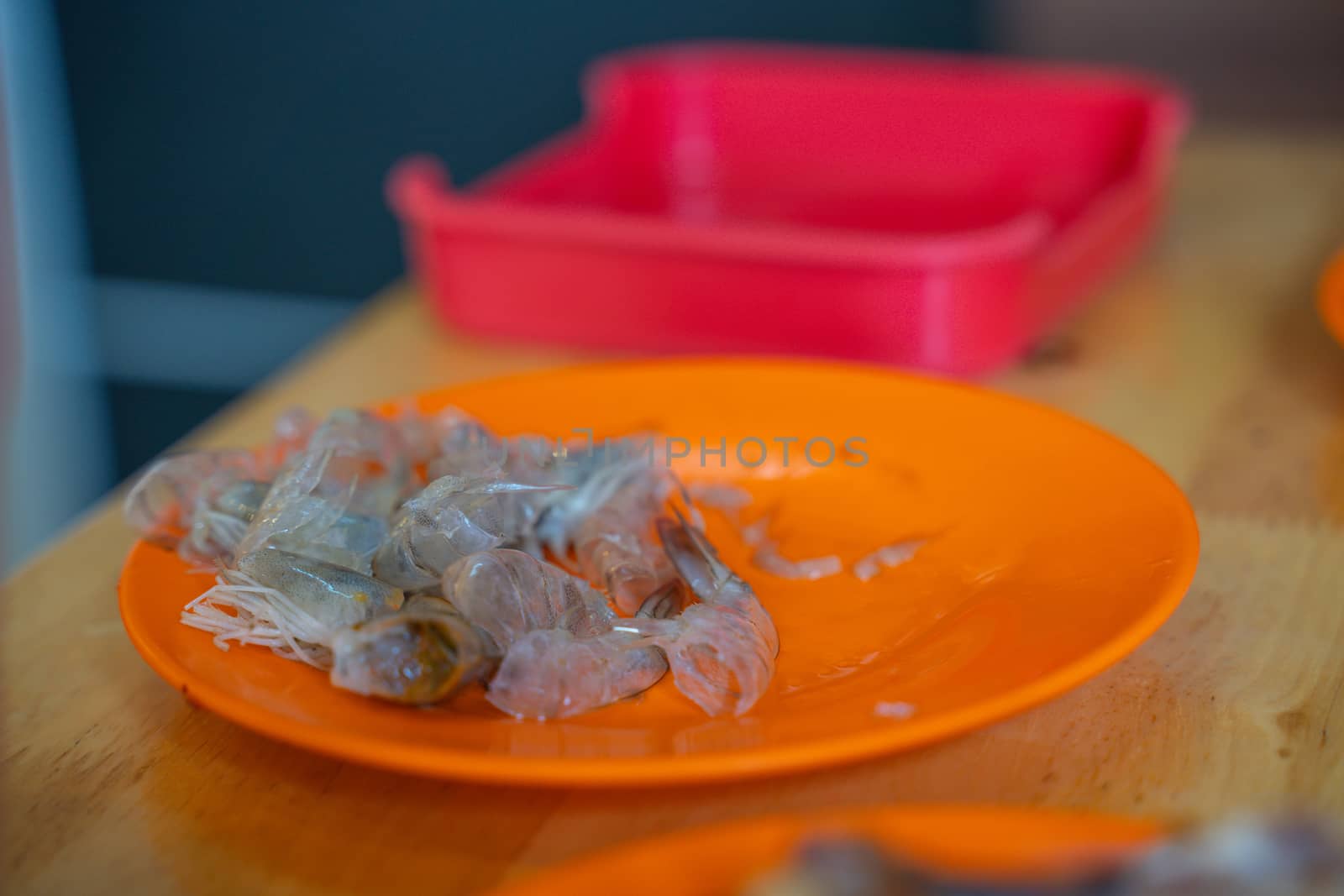 pile of peeled shrimp shell on the orange plate by peerapixs