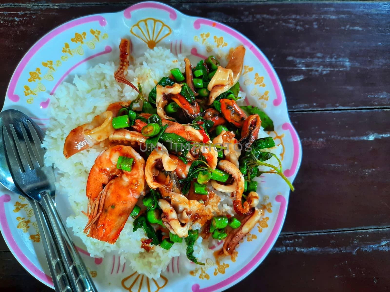 Rice topped with stir-fried seafood and basil by peerapixs
