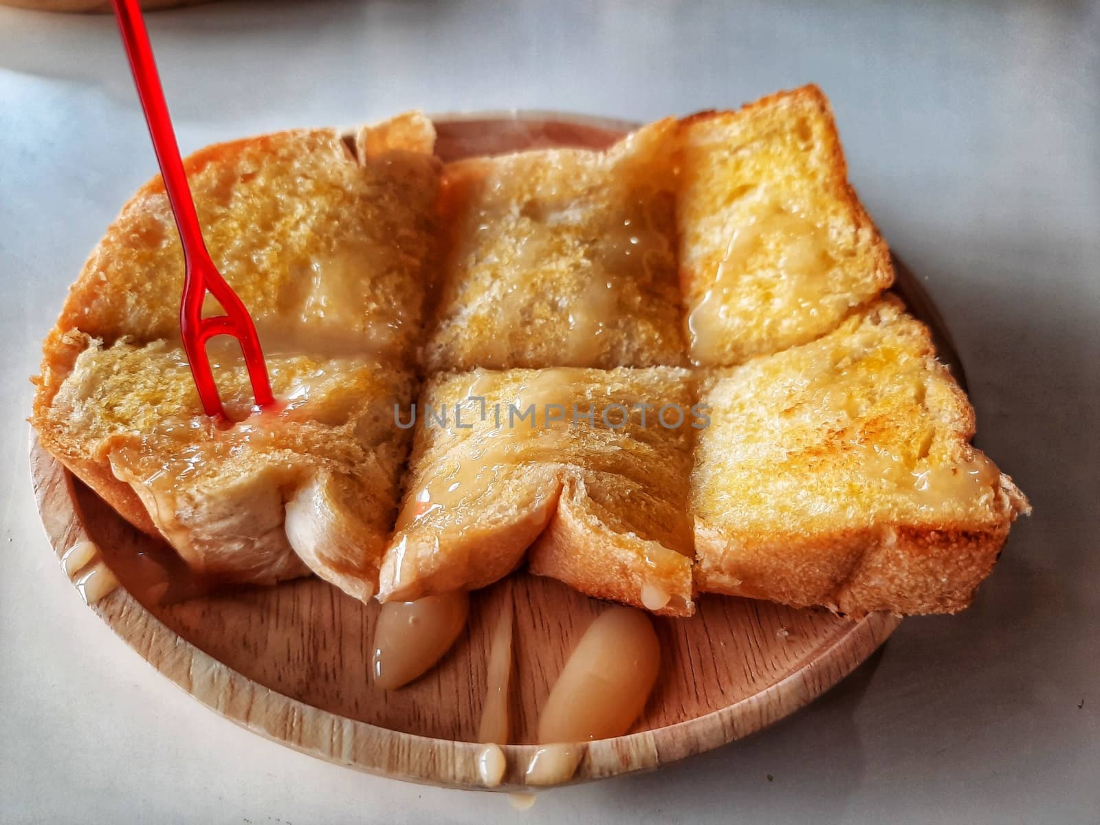 Crusty Bread Toast Slice with caramel On wooden plate Background by peerapixs
