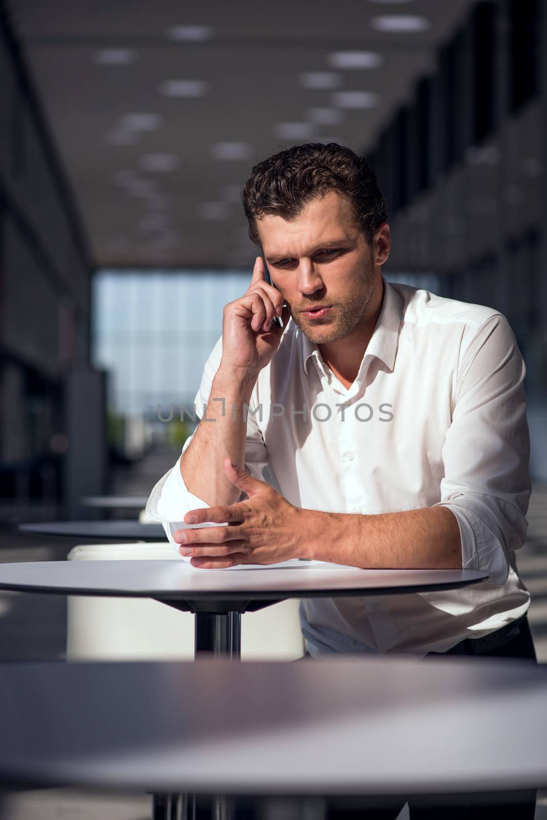 Serious businessman on coffee break using phone