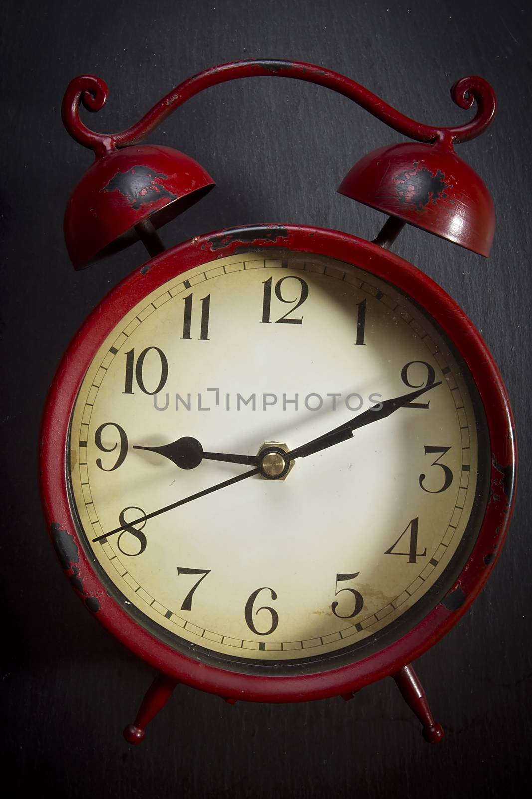 Old red alarm clock on a black background