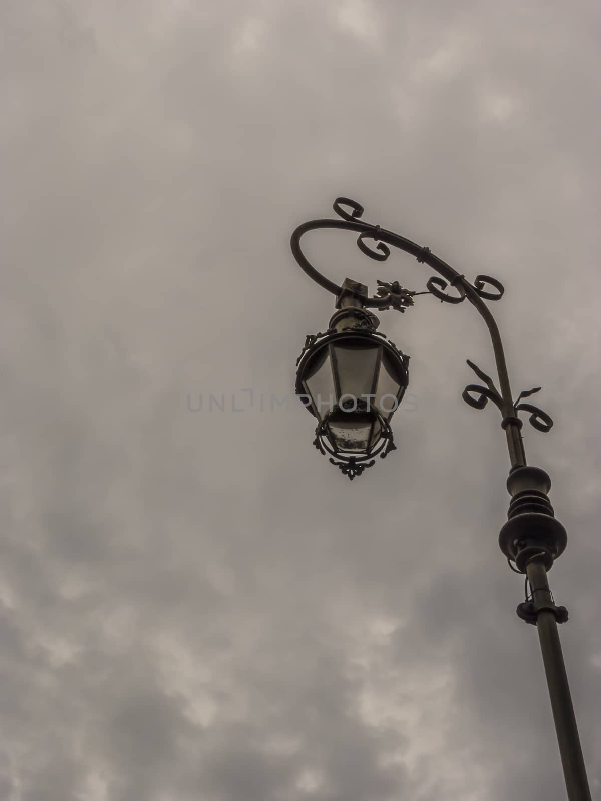 A retro lampost at a dark sky with clouds.