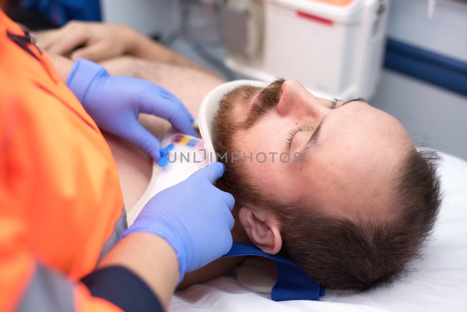 Emergency doctor putting a cervical collar to a patient in the ambulance by HERRAEZ