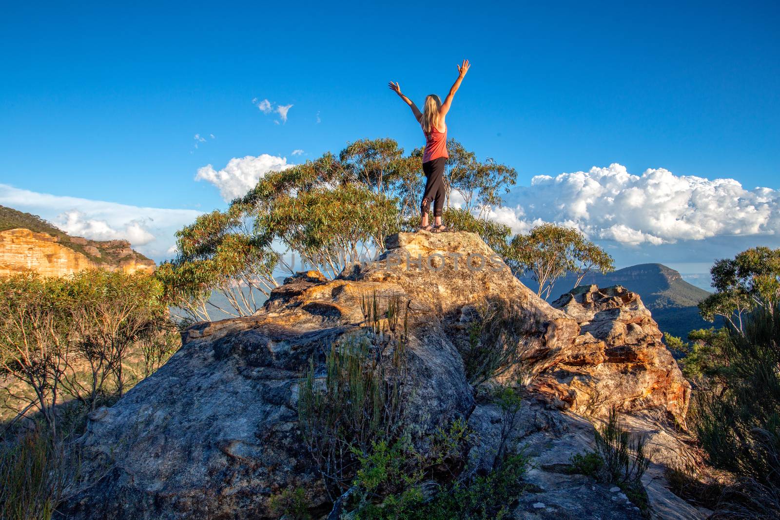 Standing at the top of the rocky peak arms outstretched in awe, success, challenge,achievement.