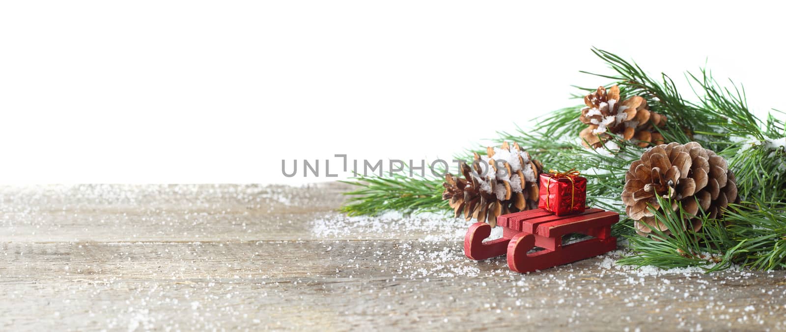 Christmas card. Pine cone and green branch on wooden table with snow, copy space for text, isolated on white background