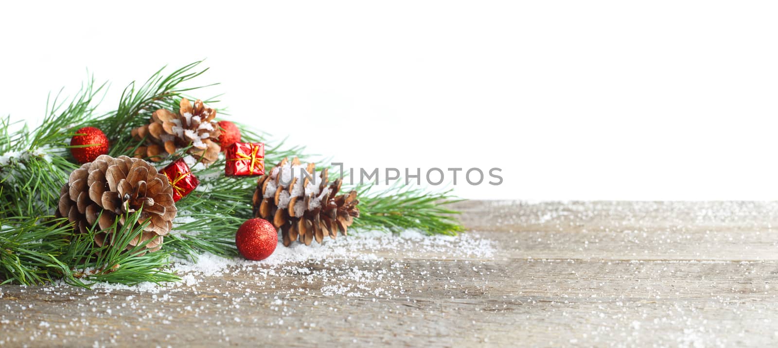 Christmas card. Pine cone and green branch on wooden table with snow, copy space for text, isolated on white background