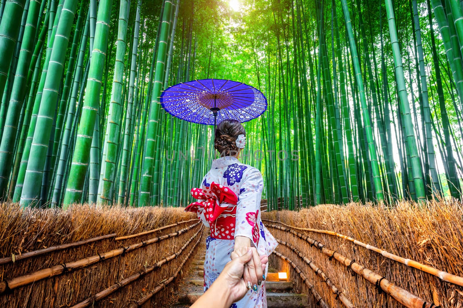 woman wearing japanese traditional kimono holding man's hand and leading him to Bamboo Forest in Kyoto, Japan. by gutarphotoghaphy