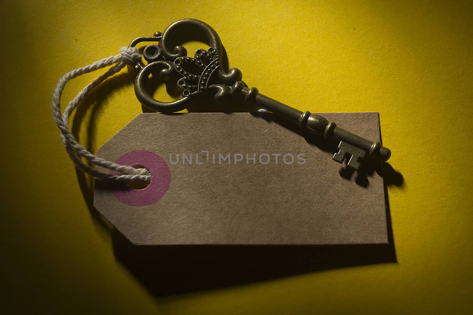 Old key with a tag on a yellow background