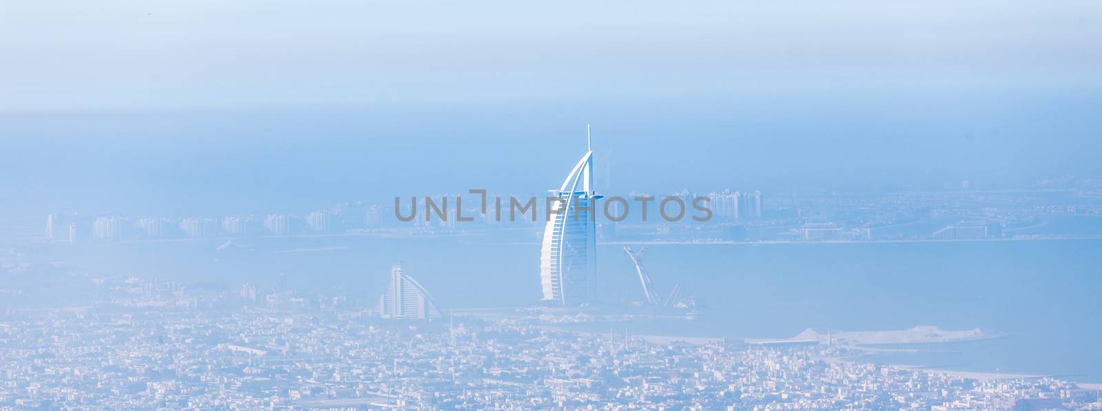 Skyline of Dubai beachfront with Burj Al Arab hotel on Jumeirah beach seen from Burj Khalifa viewpoint. Modern architecture, luxury beach resort, summer vacation and tourism concept.