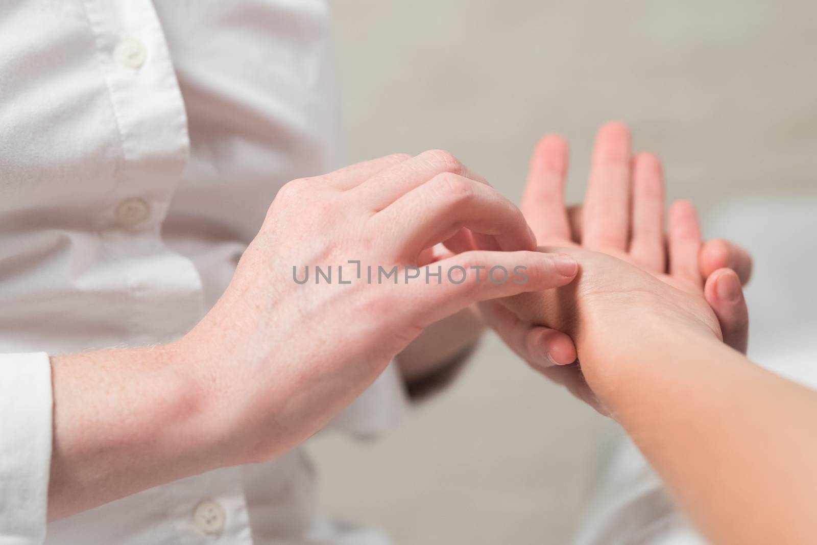 Professional female masseur giving reflexology massage to woman palm.