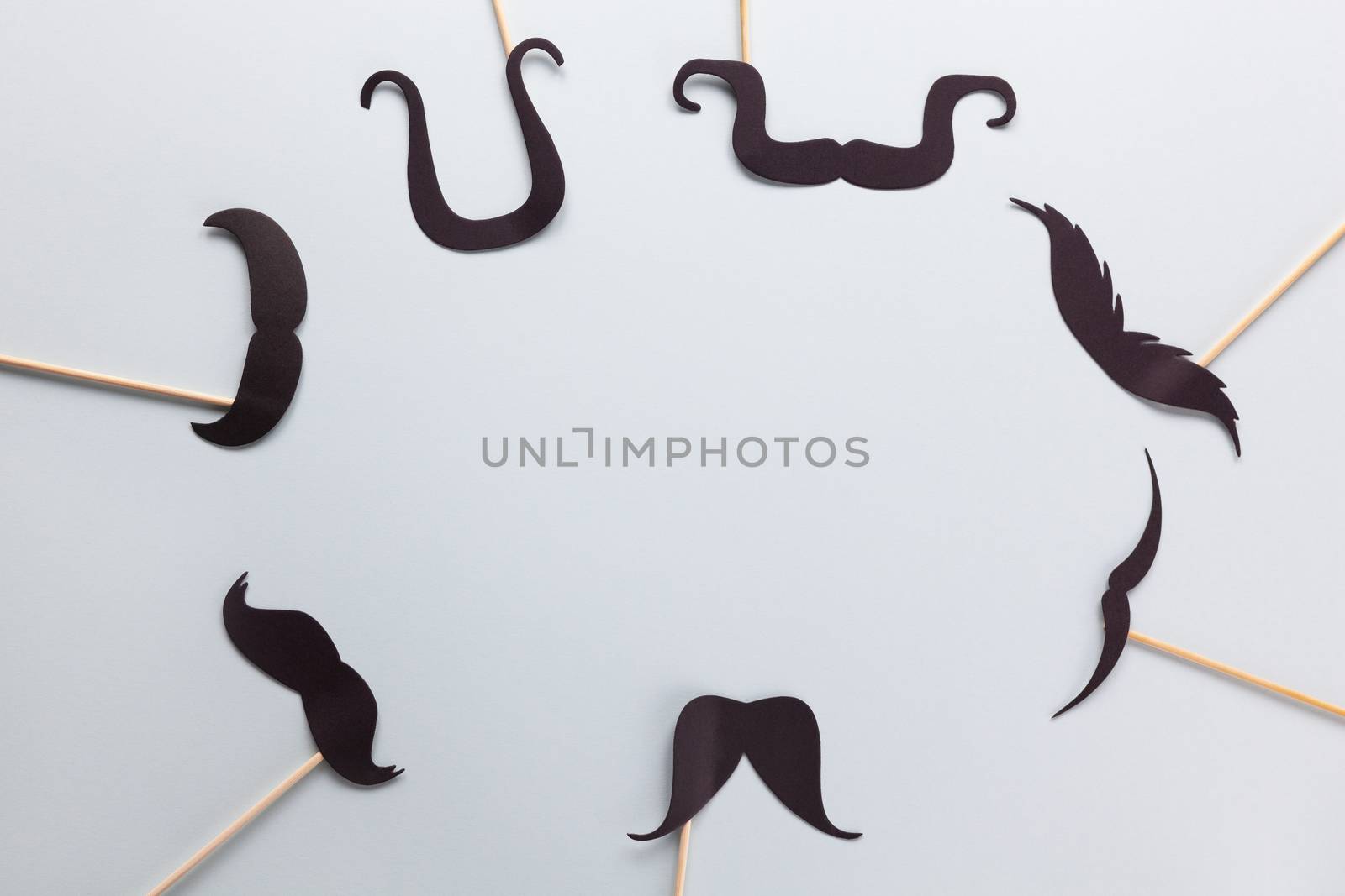 Accessories in form of black moustache on sticks on grey background with place for text. Concept movember, men's health, prostate cancer awareness month, charity, Father's Day. Horizontal. Flat lay.