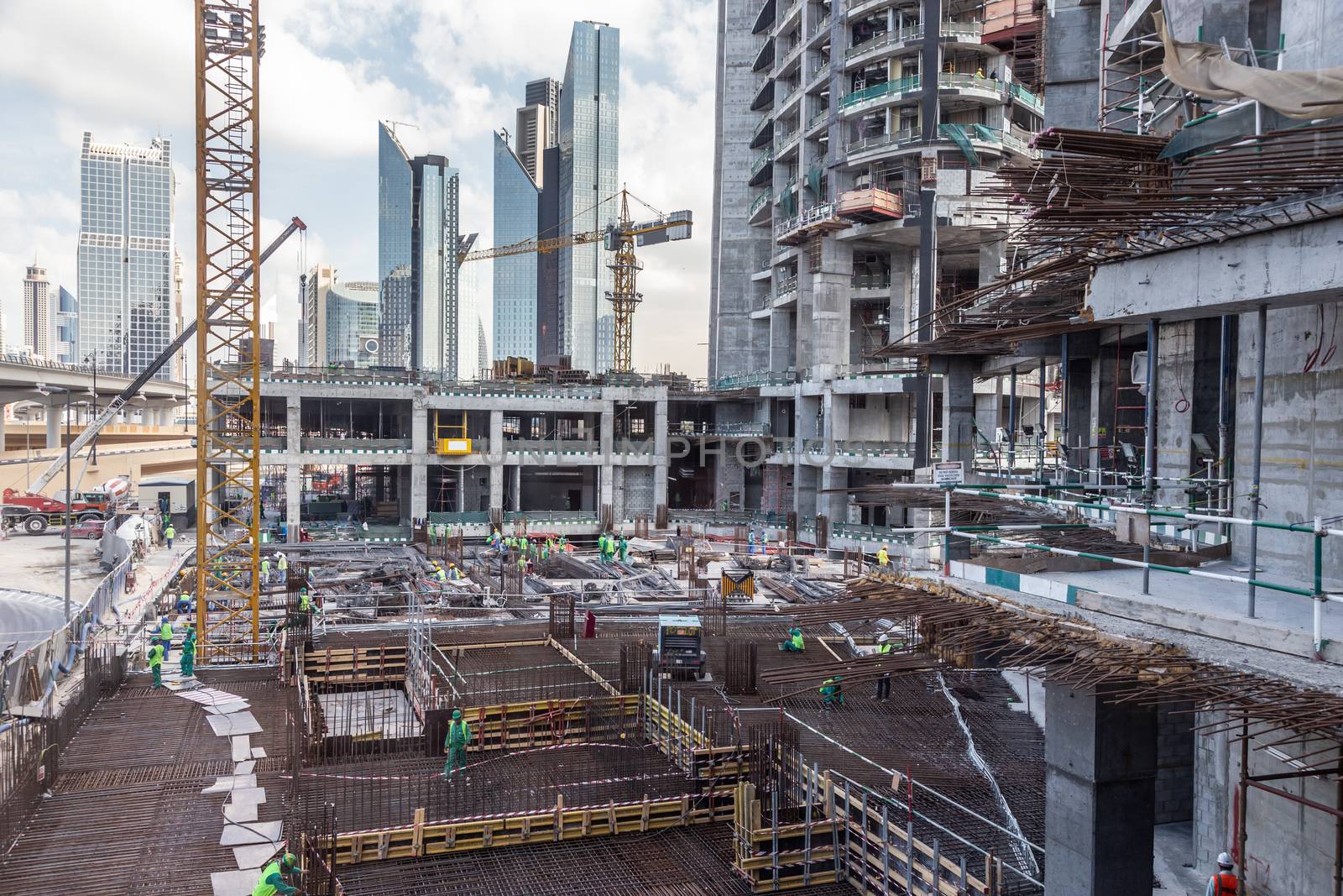 Laborers working on modern constraction site works in Dubai. Fast urban development consept.