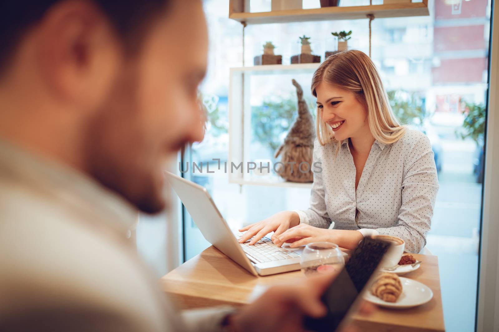 Beautiful young smiling woman working at laptop on coffee break in a cafe. Selective focus. Focus on businesswoman.