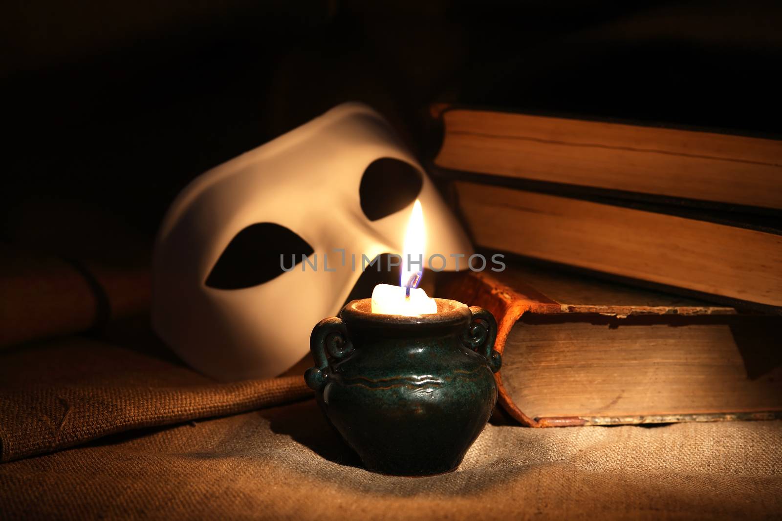 Vintage still life with candle near mask and books