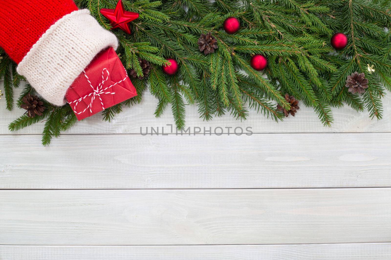 Christmas new year flat lay decor of fir branches, sock and gift on white toned natural wooden plank background texture provence style with copy space for text