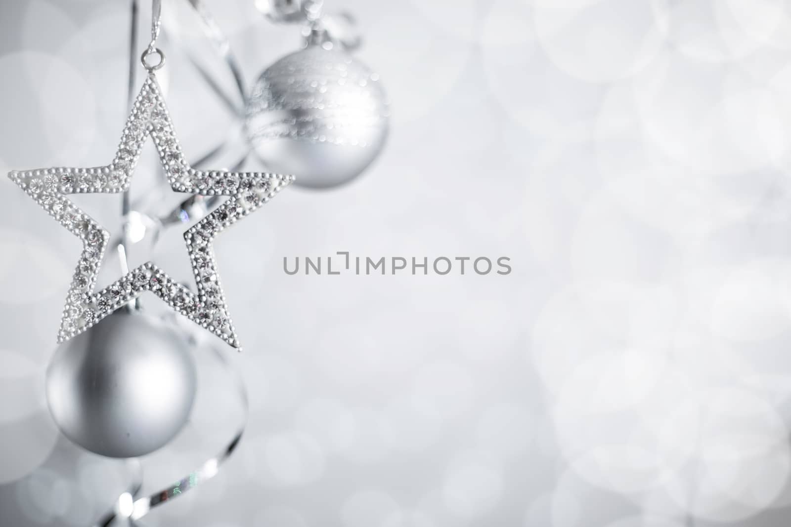 Silver Christmas new year balls and star with curly streamer ribbon bow over glittering bokeh lights background with copy space for text