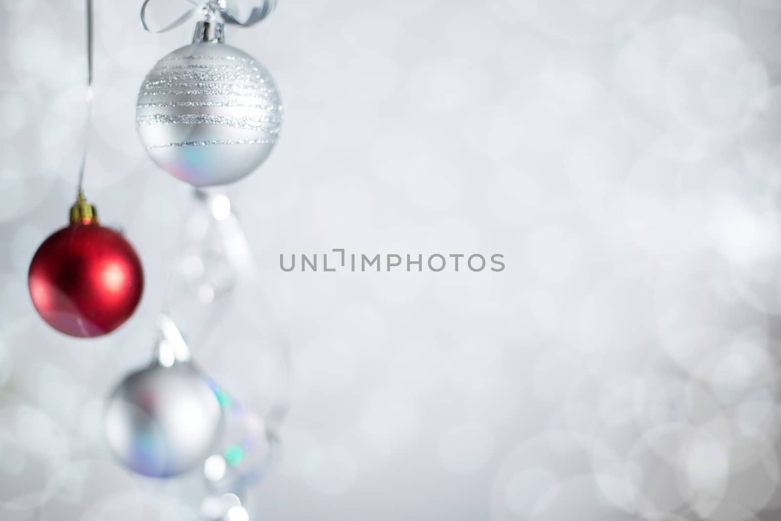 Silver and red Christmas new year balls with curly streamer ribbon bow over glittering bokeh lights background with copy space for text