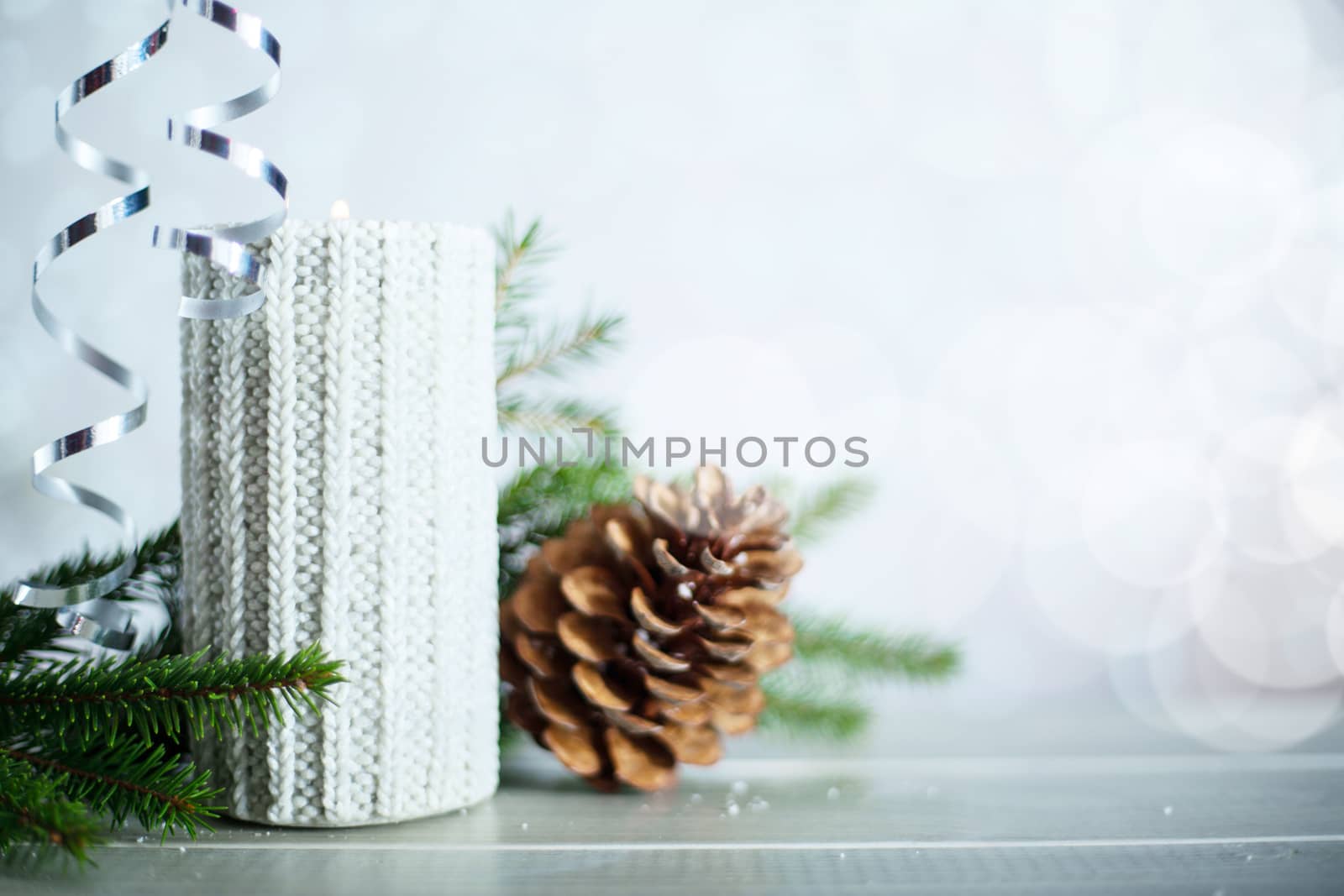 Silver Christmas new year candle with curly streamer ribbon bow decoration over glittering bokeh lights background with copy space for text