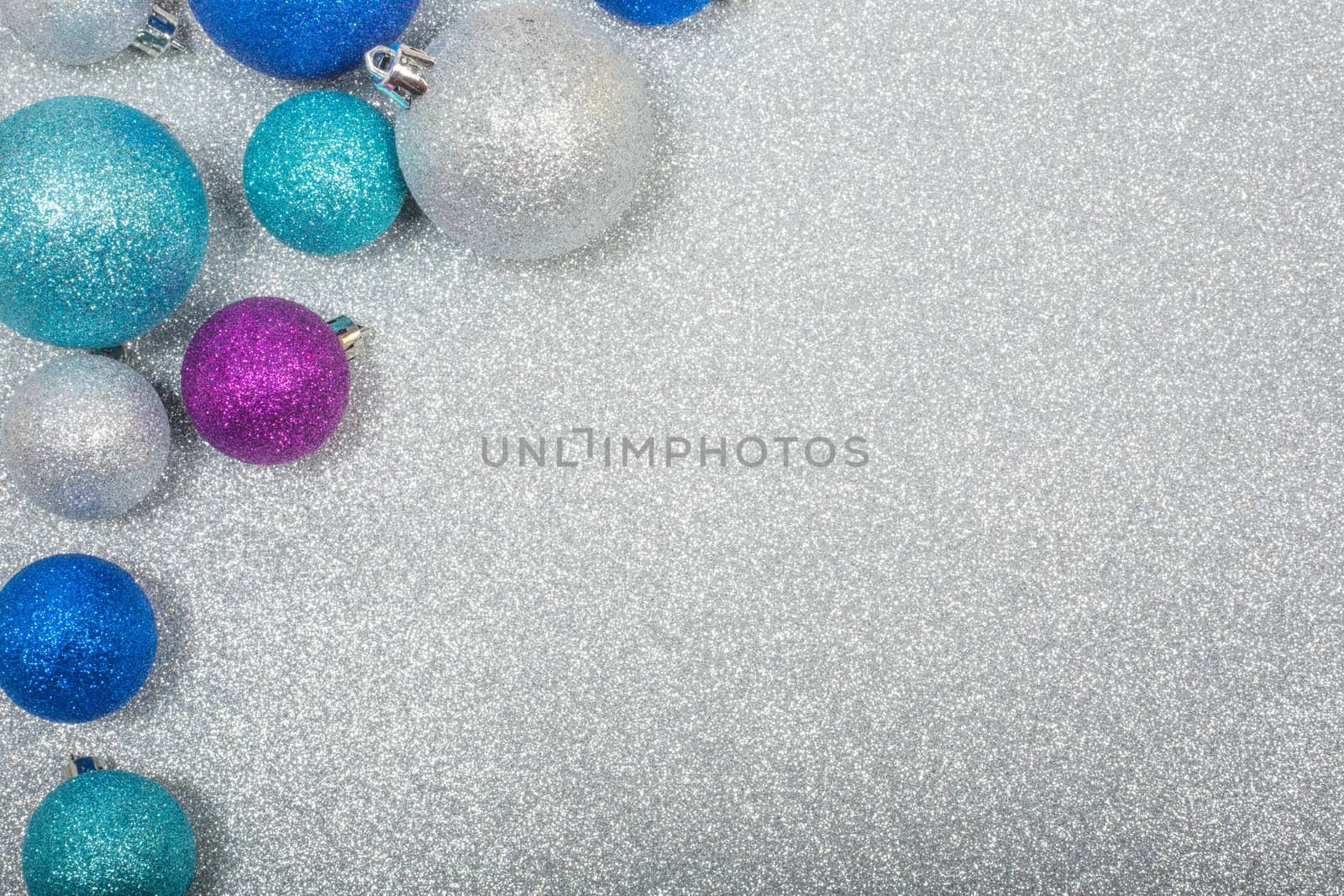 Christmas decoration of colorful glitter balls on silver glitter background with copy space for text new year card concept