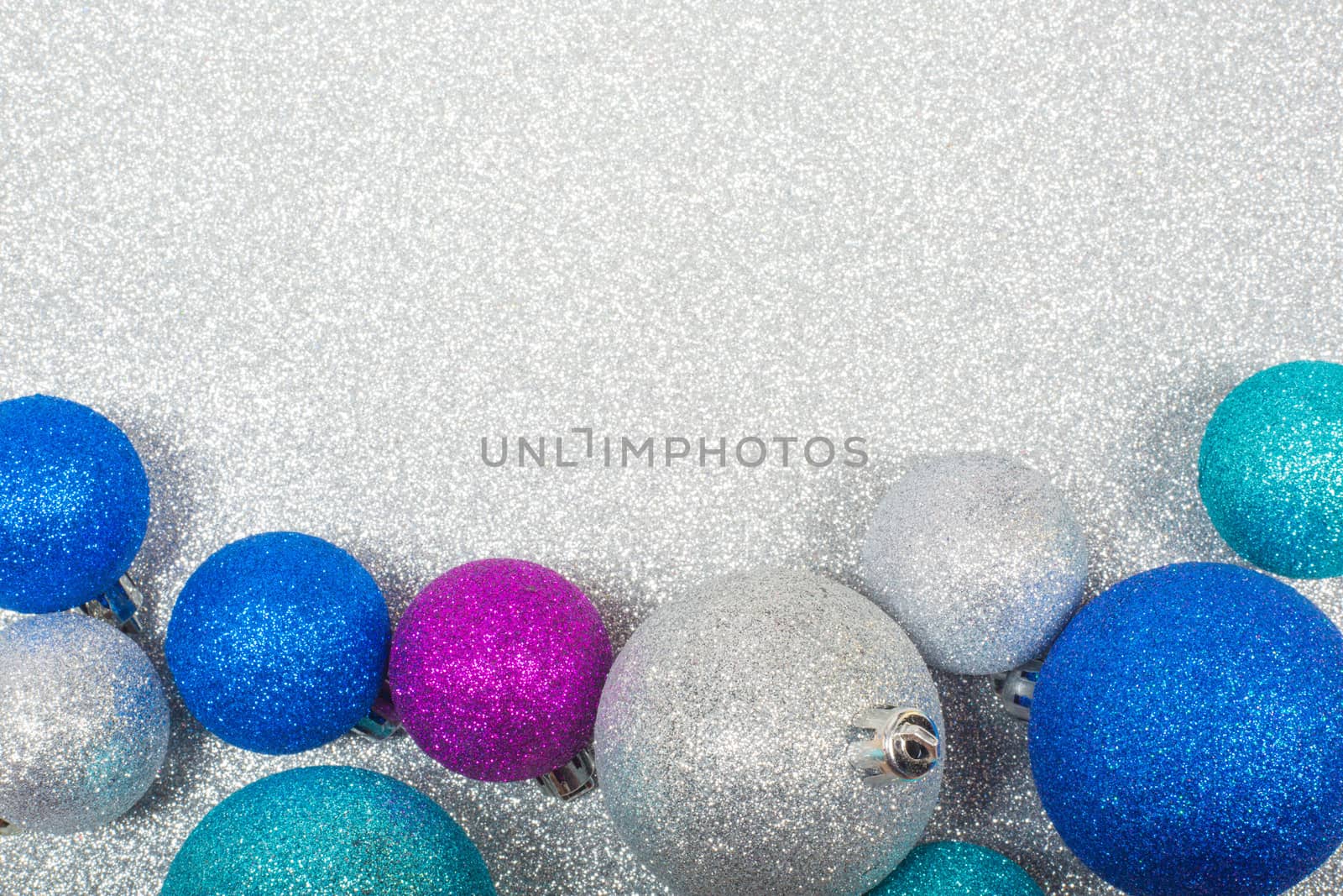 Christmas decoration of colorful glitter balls on silver glitter background with copy space for text new year card concept