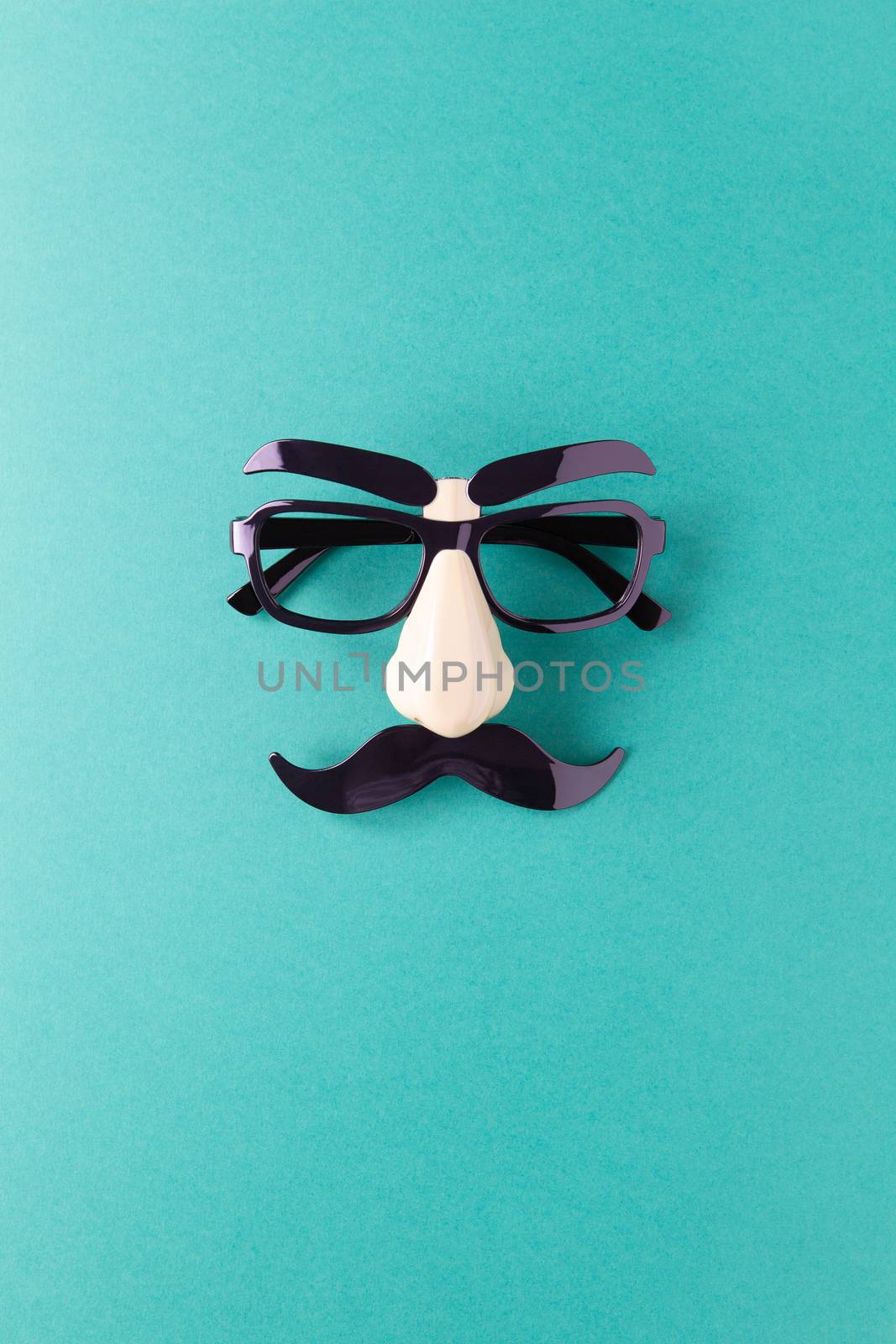 Carnival mask with moustache, nose and glasses on blue background, copy space. Concept Movember, men's health, prostate cancer awareness month, charity, Father's Day. Vertical. Minimalism flat lay.