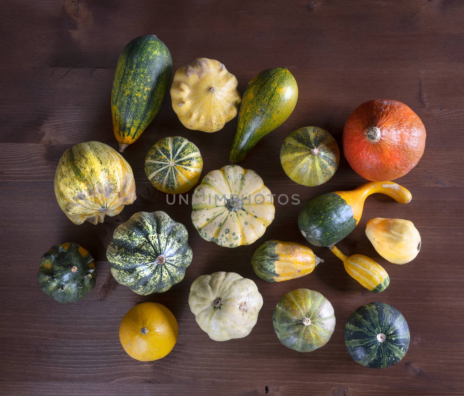 Some small pumpkins on a wooden table in the autumn with some leaves