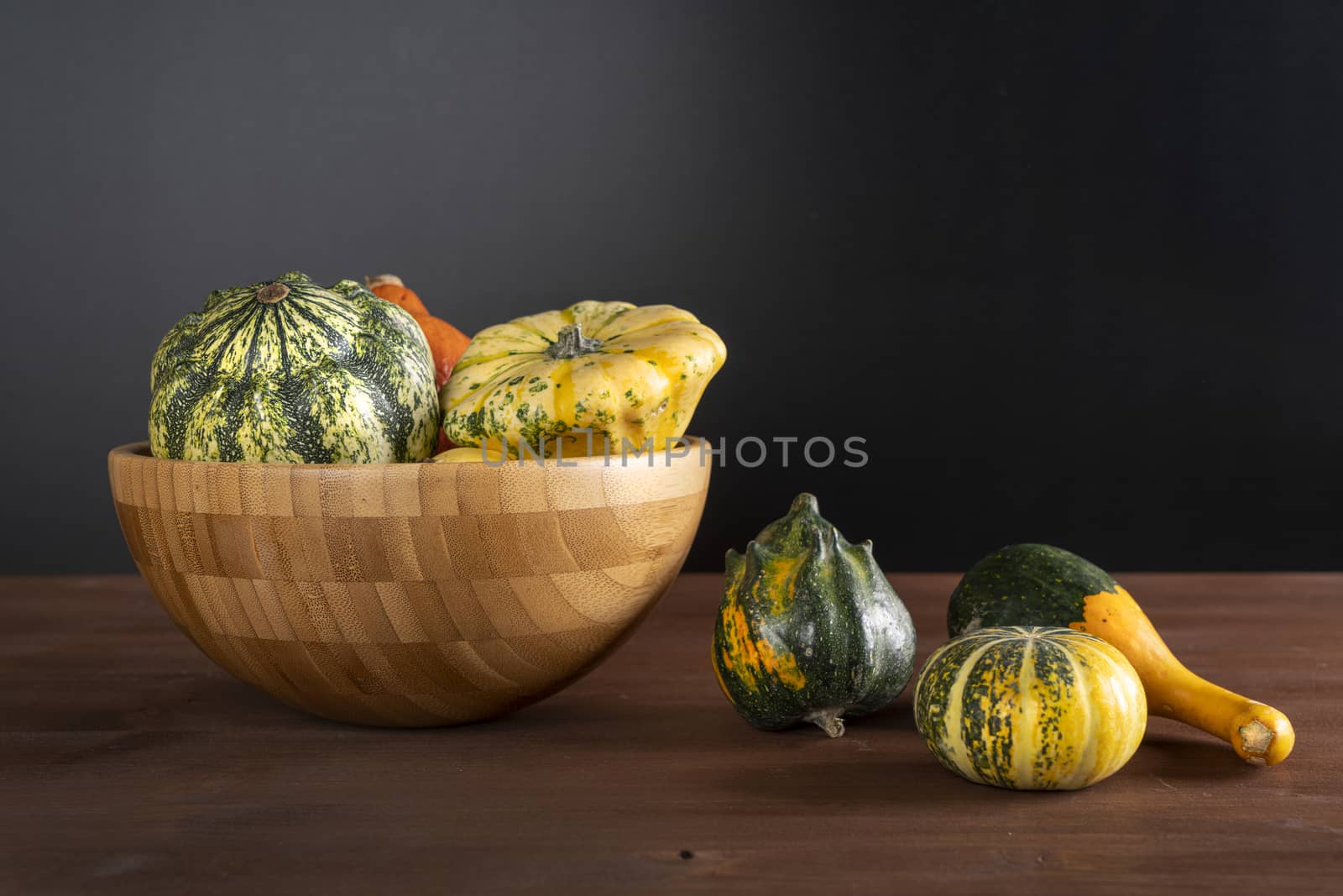 Some small pumpkins on a wooden table in the autumn with some leaves