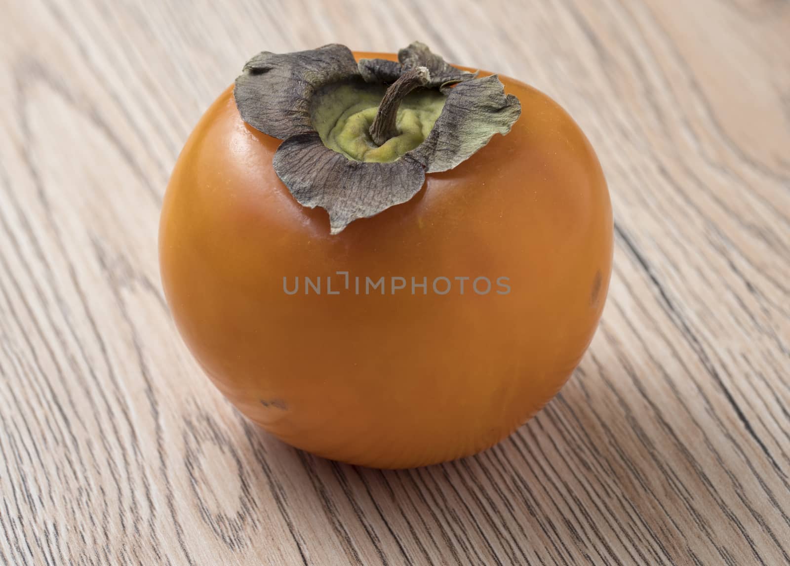 Whole ripe persimmon fruit on wooden background. Close up view.