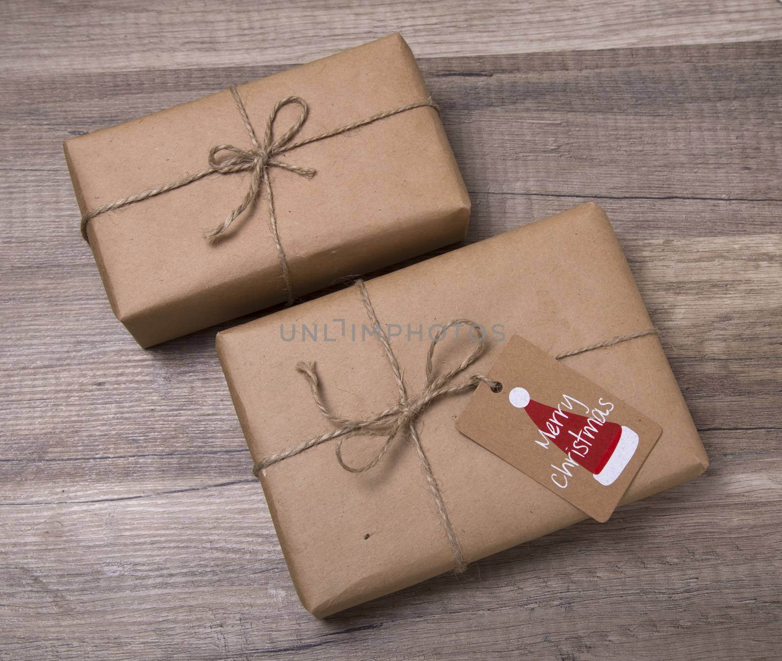 Christmas or New Year gift boxes wrapped in kraft paper with blank gift tag on old wooden background.