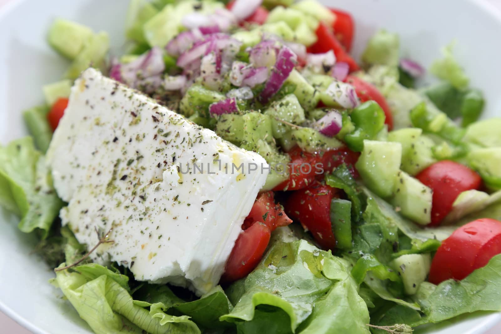 Greek salad with lettuce, tomatoes, cucumbers, peppers, red onion, oregano and feta