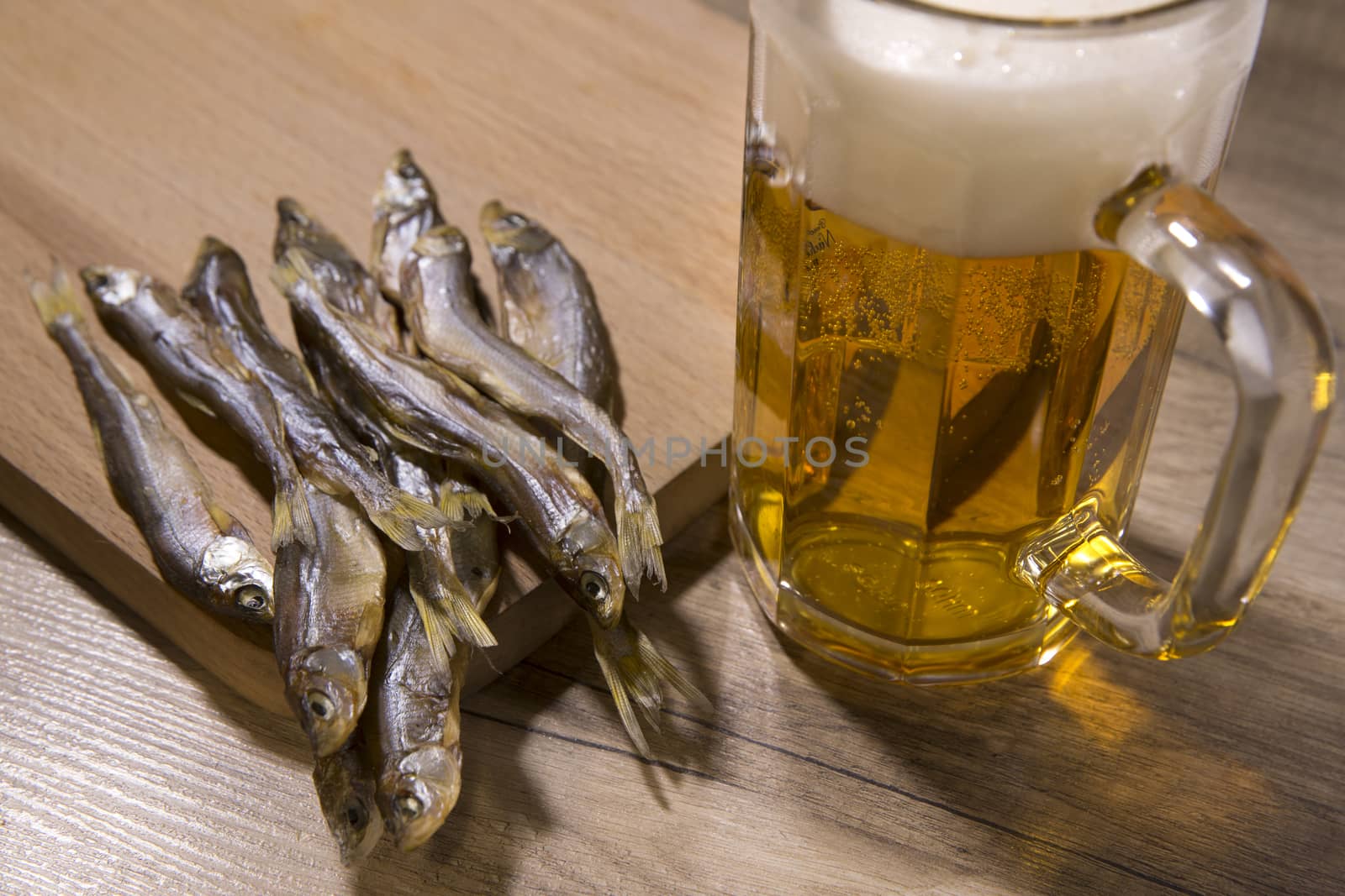 Beer mug and dried fish on wooden table.