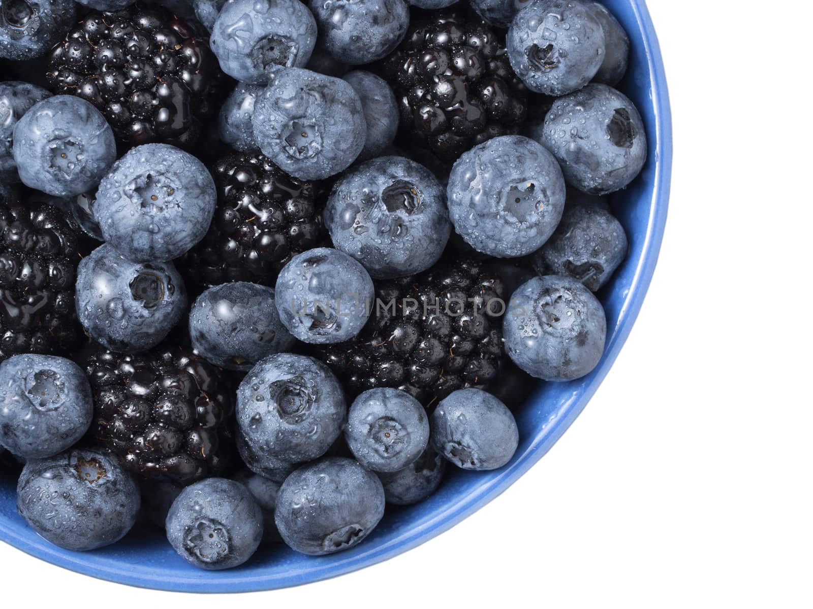 Bowl full of fresh blackberries and blueberries on white background.