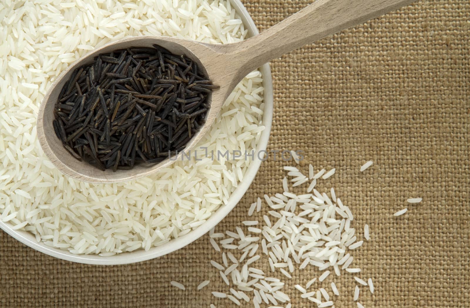 two varieties of rice, white in a round bowl, and black in a wooden spoon.  
