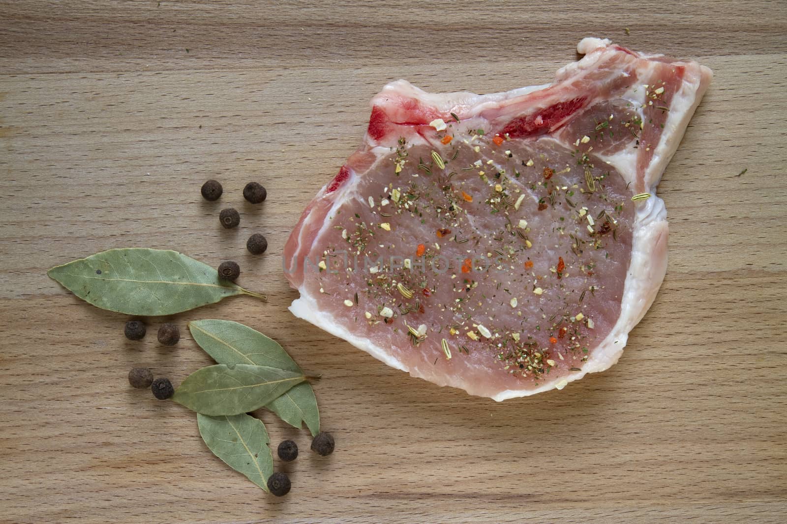 raw pork chop on a cutting board with spices