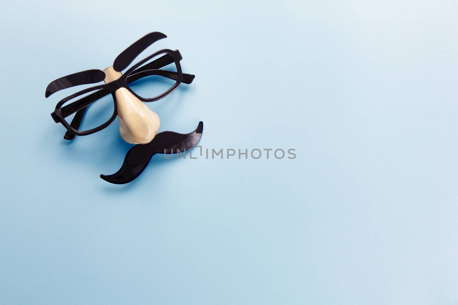 Carnival mask with moustache, nose and glasses on blue background, copy space. Concept men's health, prostate cancer awareness month, charity, Father's Day. Horizontal. Minimalism flat lay.