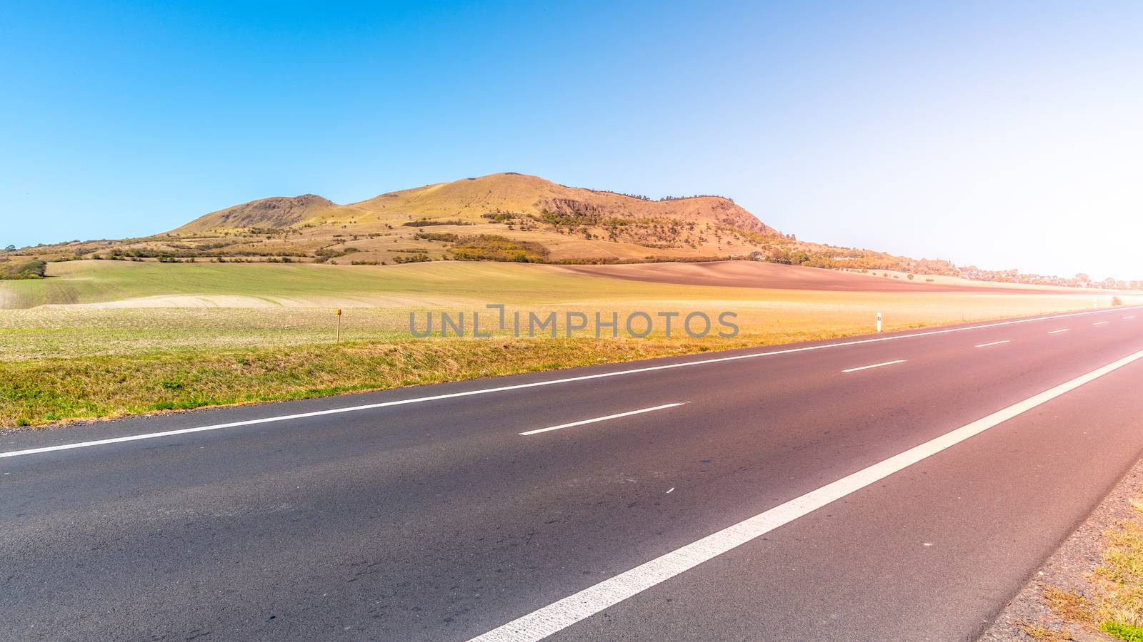 Rana Mountain and asphalt road near Louny in Central Bohemian Highlands on sunny summer day, Czech Republic.