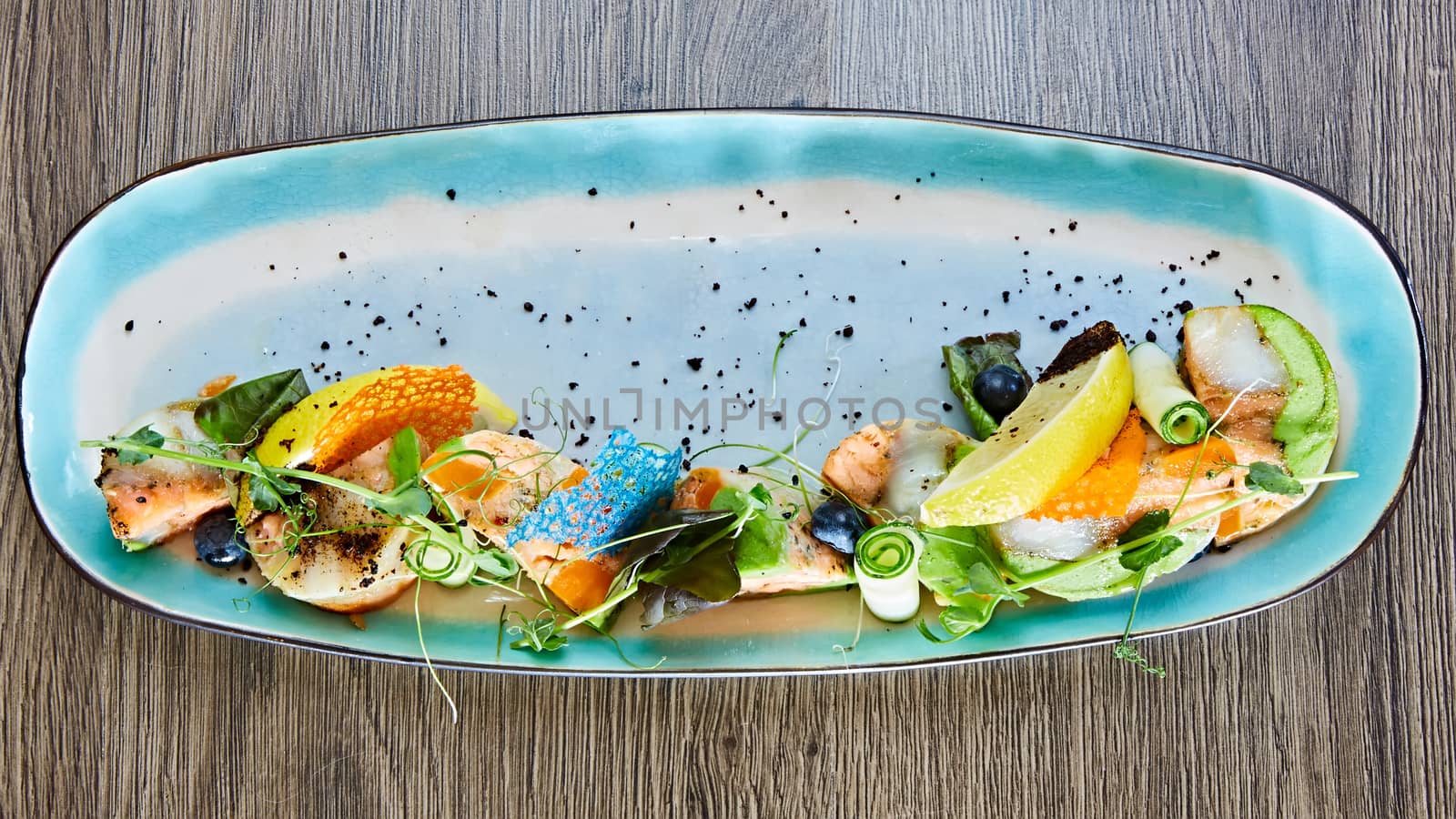 fried fish rolls with herbs and vegetables on blue plate