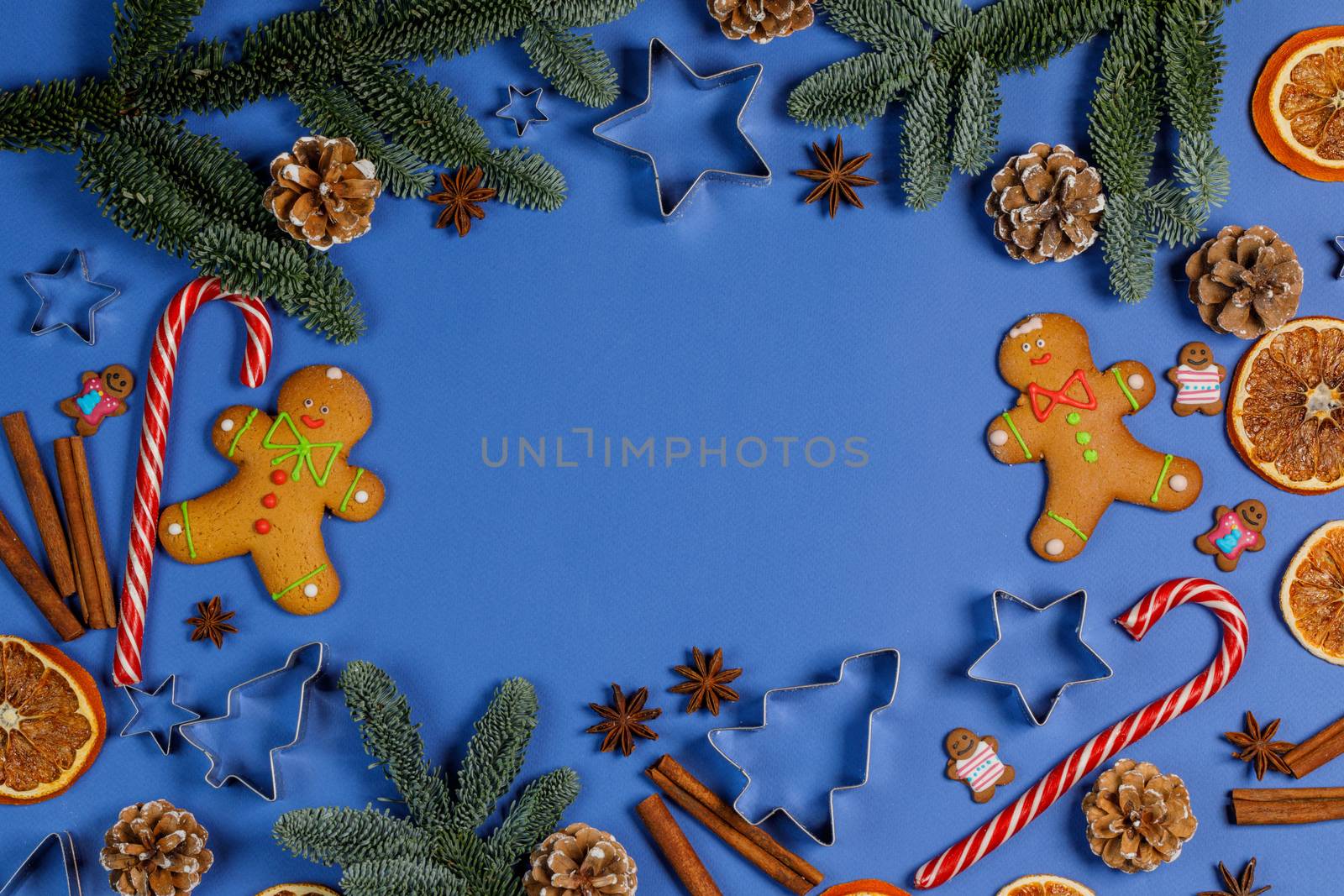 Christmas food frame. Gingerbread cookies, spices and decorations on blue background with copy space