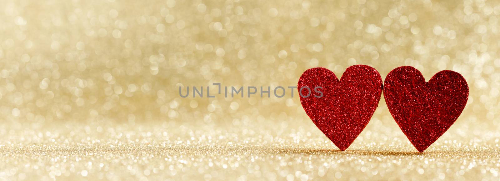 Two red wooden hearts on golden glowing bokeh hearts background for Valentines day