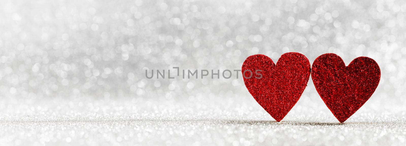 Two red wooden hearts on silver glowing bokeh hearts background for Valentines day