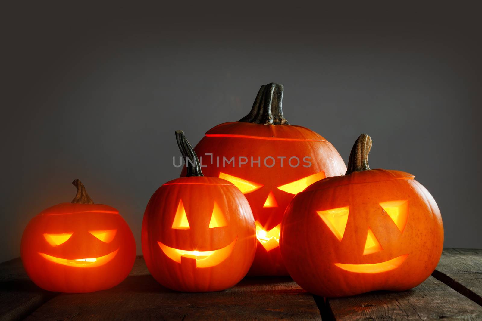 Halloween pumpkin head jack o lantern and candles on wooden background