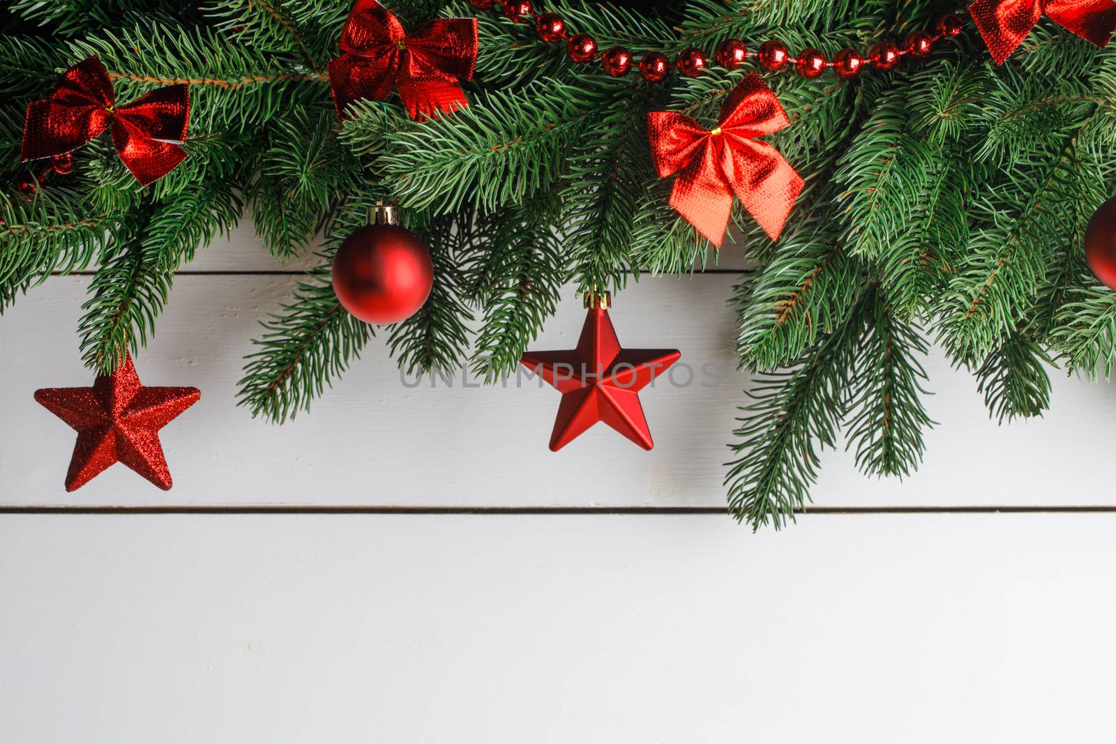 Christmas decoration frame on wooden background, fir tree branch, red baubles, bows and stars