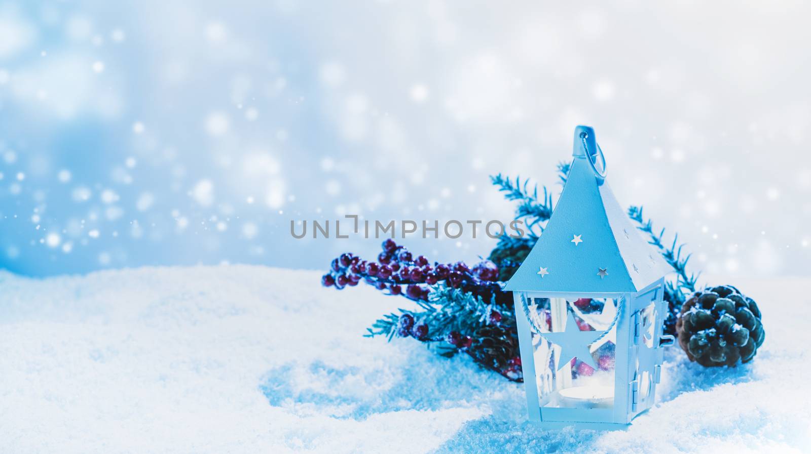 Burning candle in lantern and christmas decoration on snow