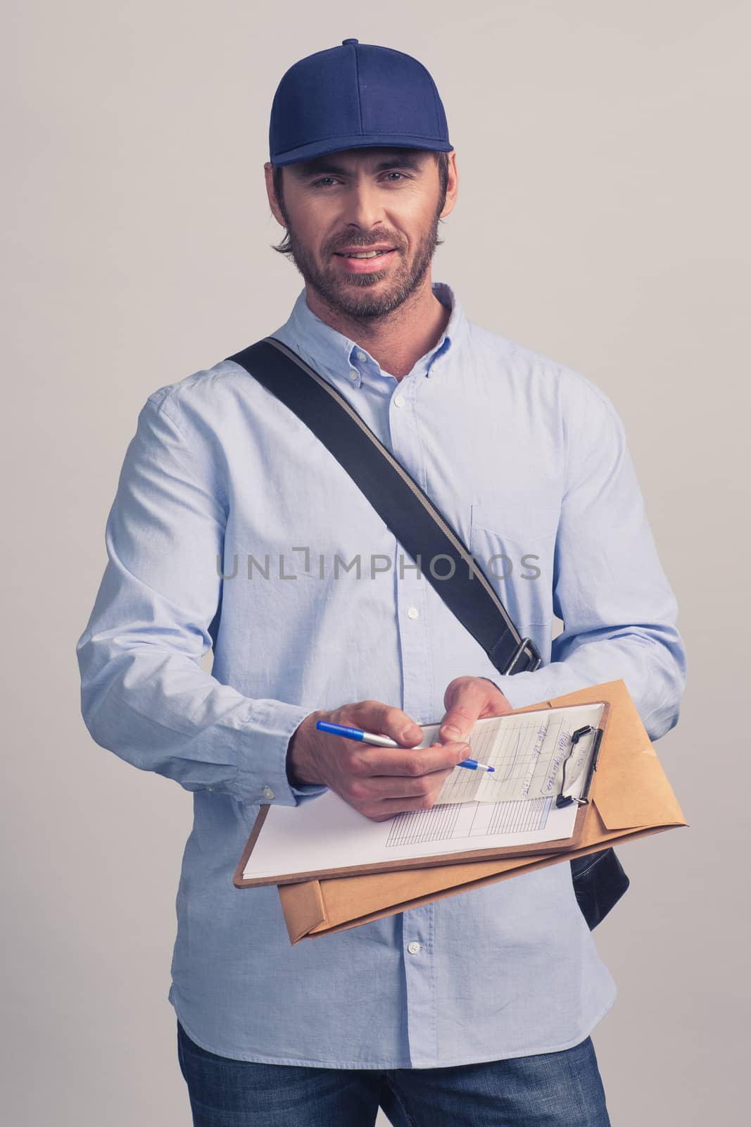 Man in blue uniform holding delivery form on clipboard for delivery