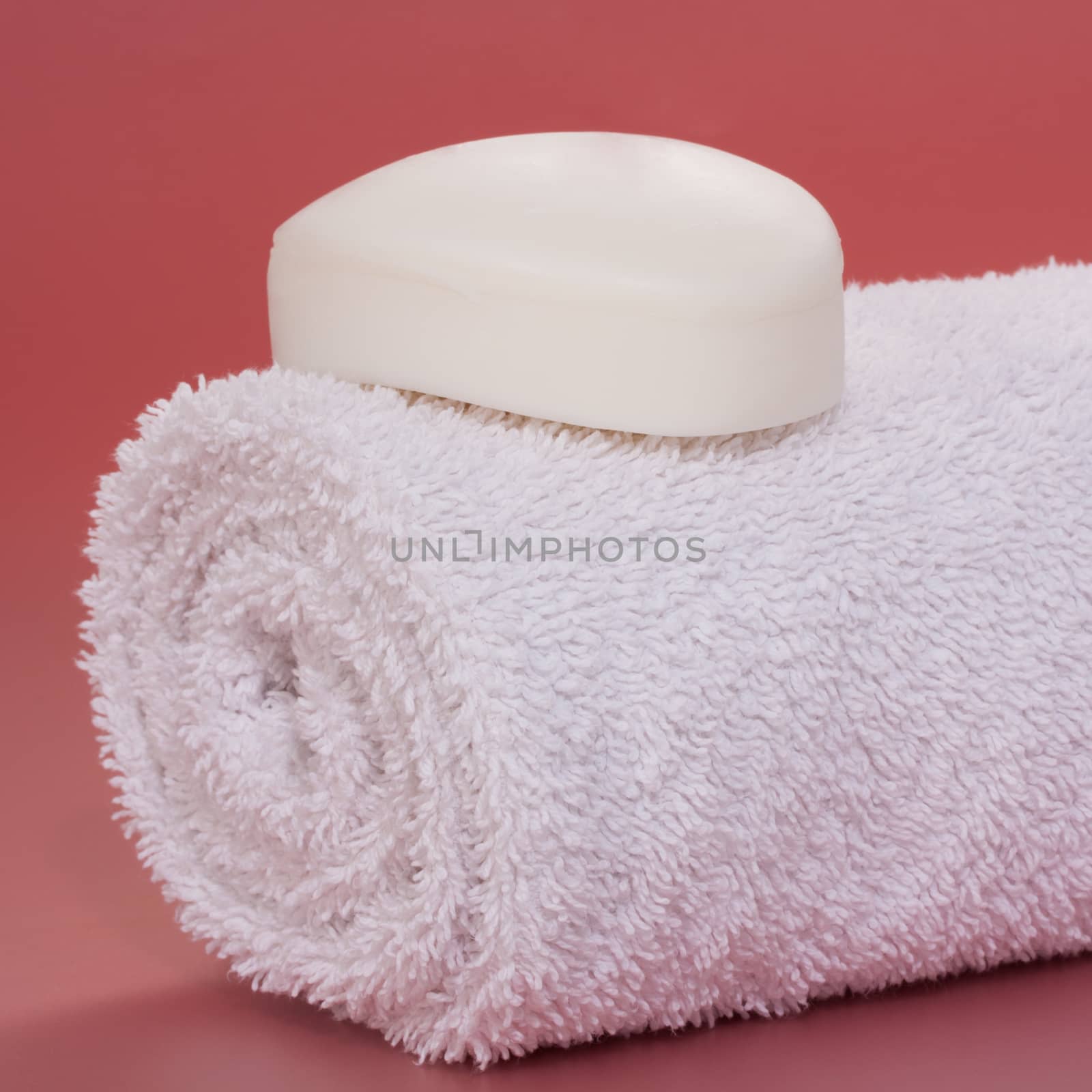 White soap bar placed over a rolled clean bath towel