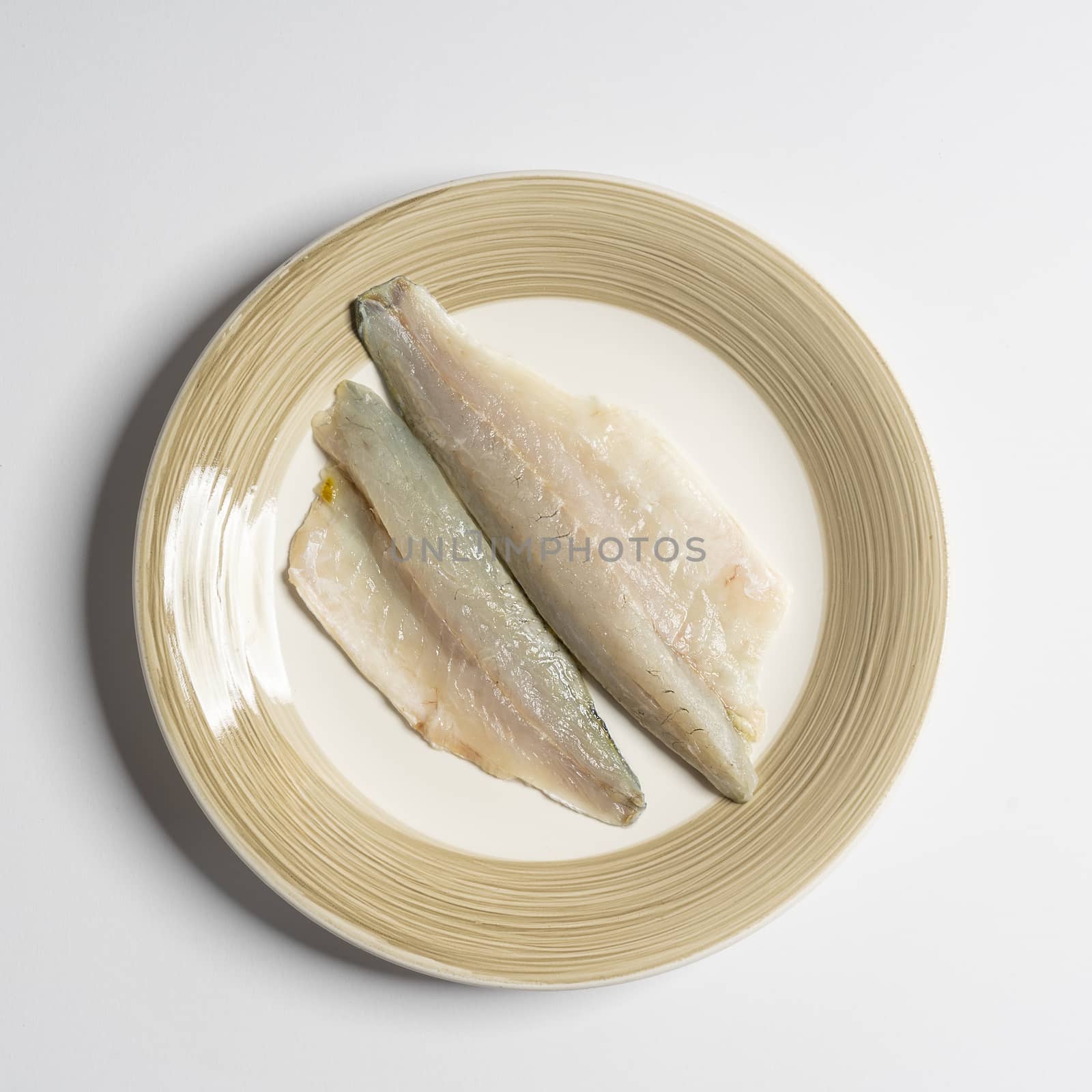 a dish with two fillets of sea bream on a white surface