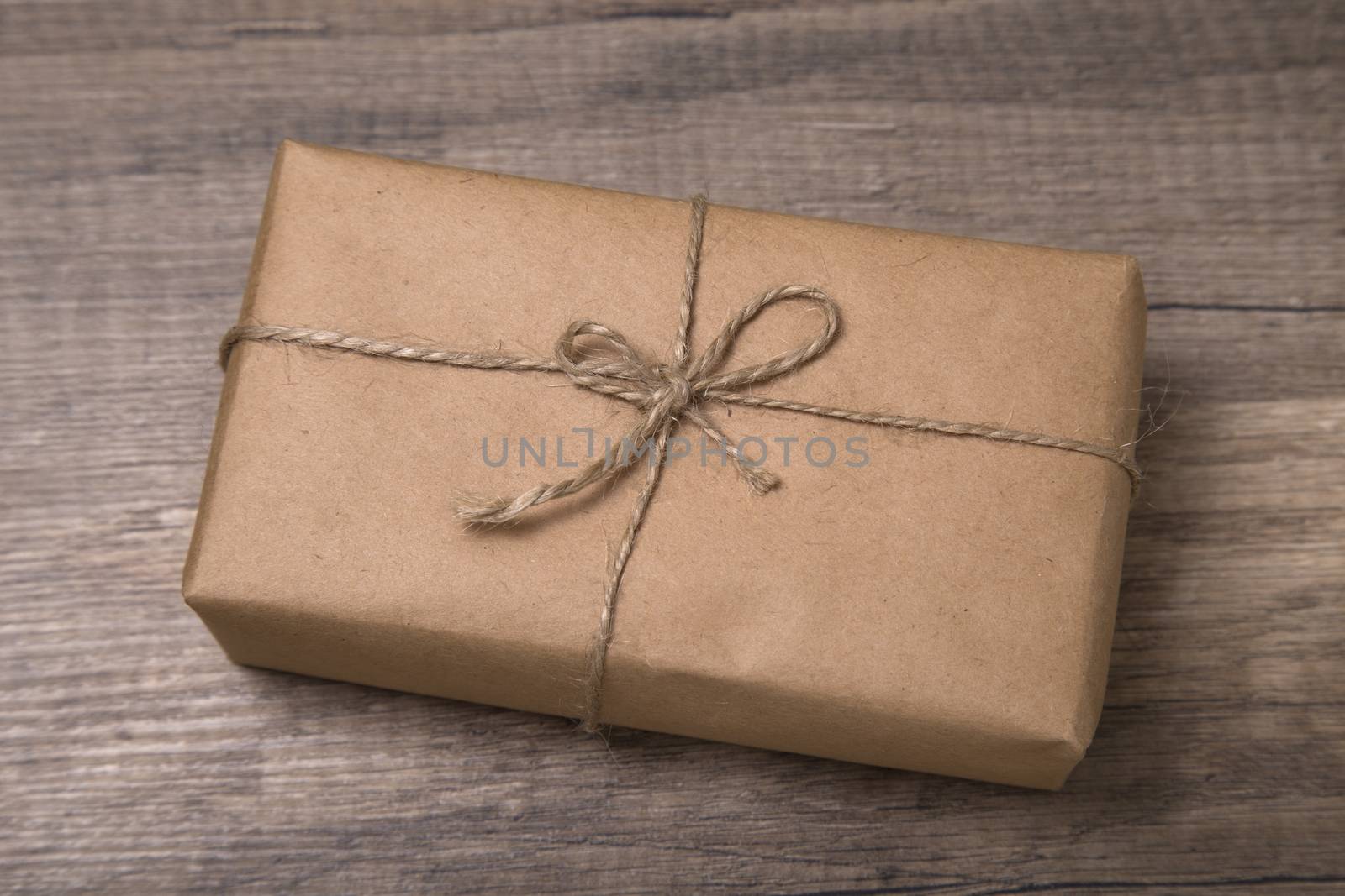 Christmas or New Year gift box wrapped in kraft paper on old wooden background.