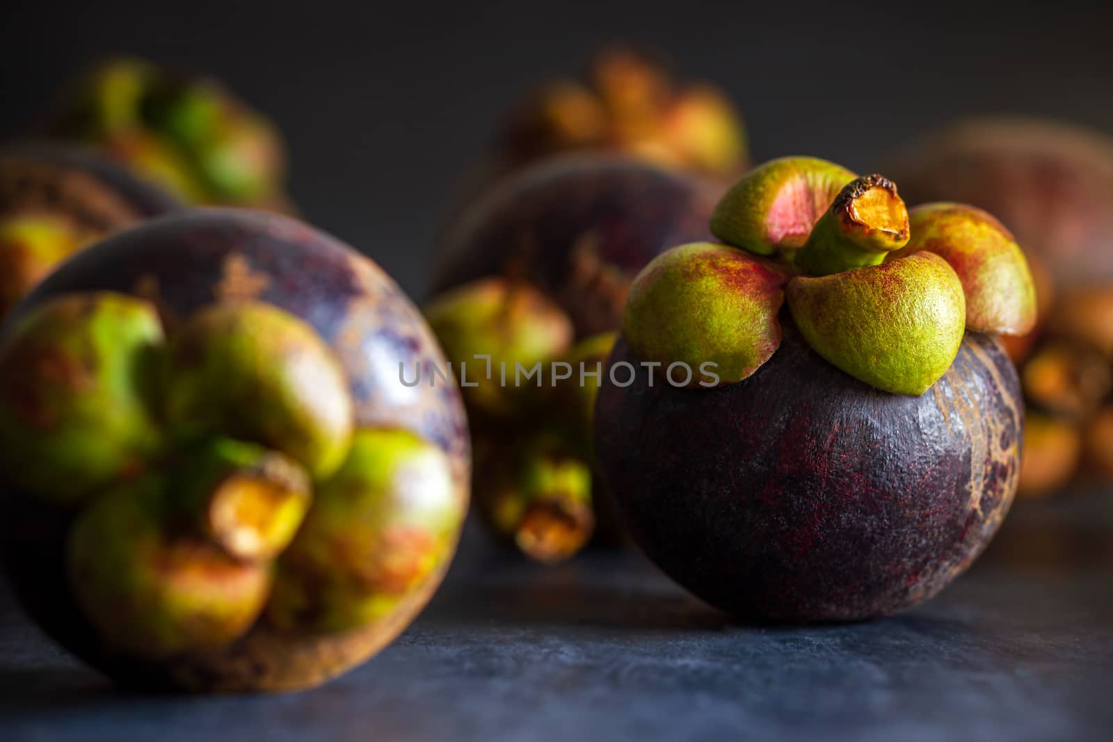 Mangosteen fruit on black cement floor and morning light. Is a seasonal fruit in Thailand. Closeup and copy space for text.