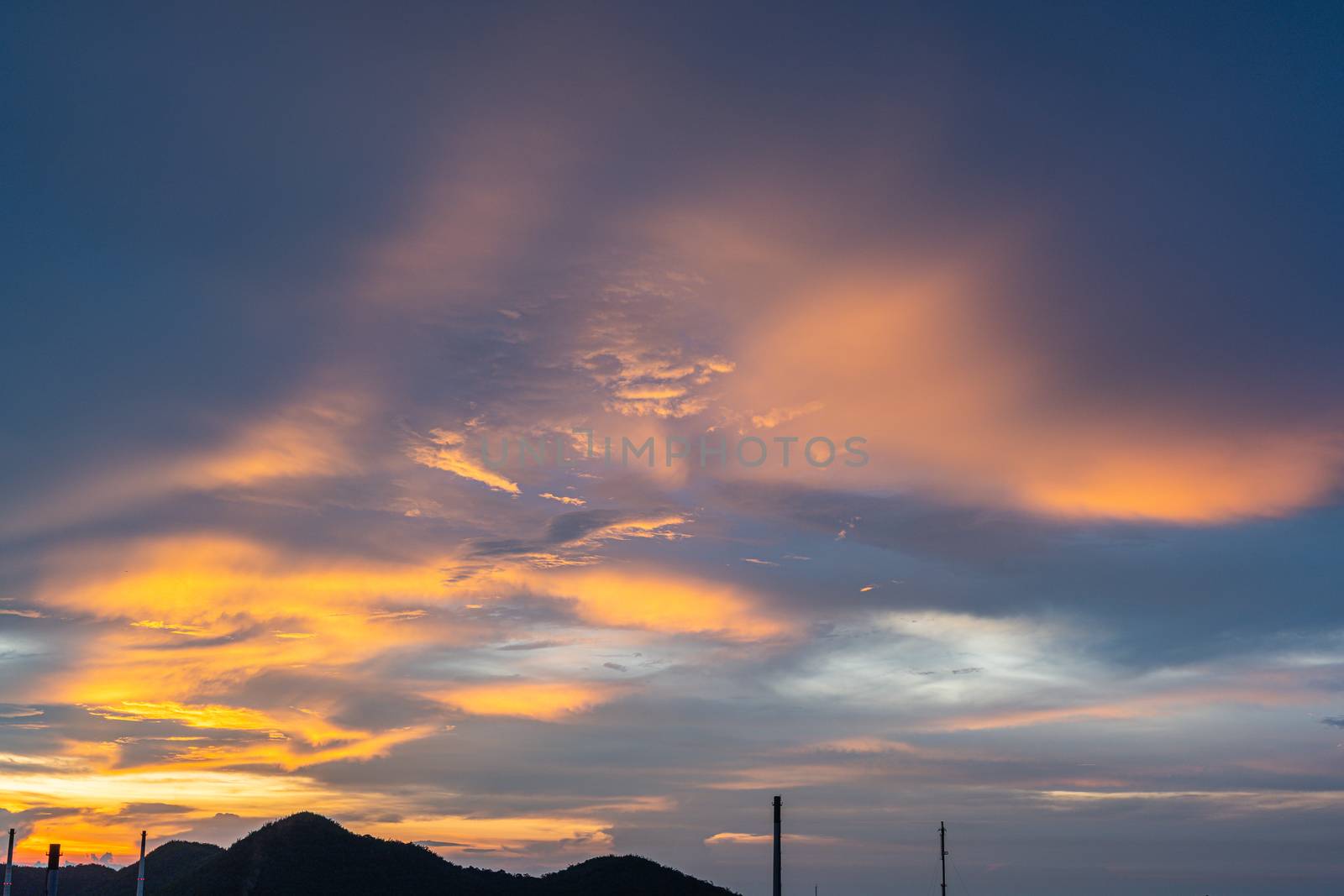 The Bright orange and gold colors of the sunset sky. Summer sky with clouds during the sunset, landscape with a sky view over the hill