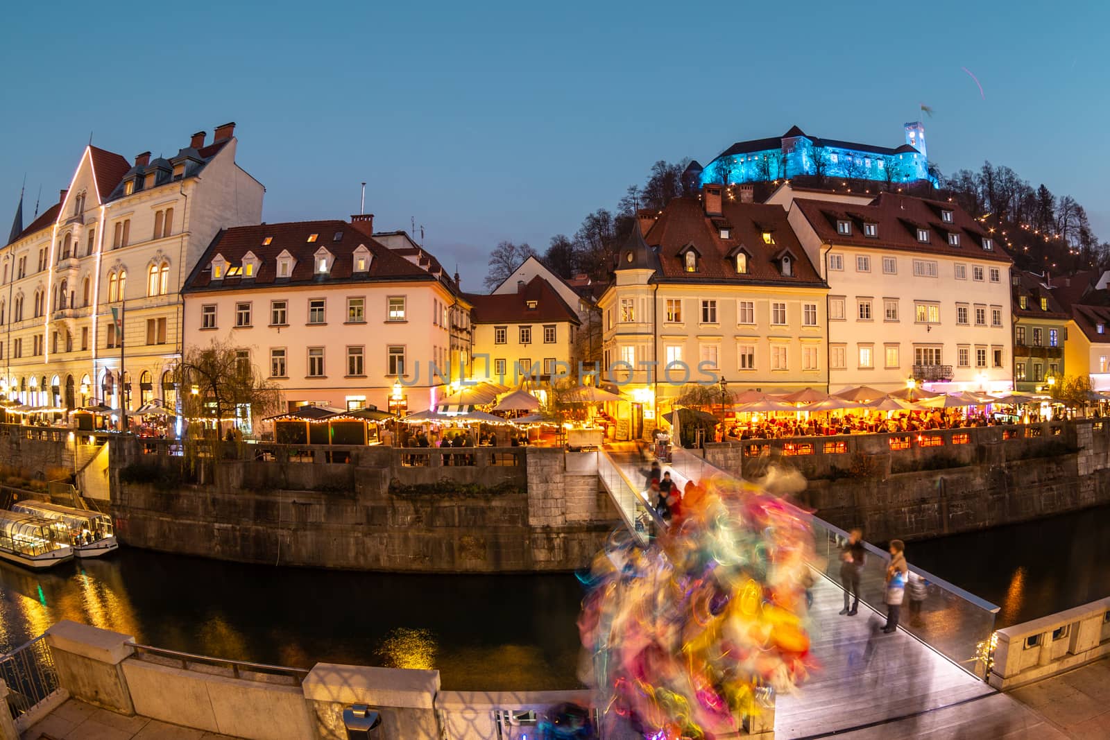 View of lively river Ljubljanica bank in old city center decorated with Christmas lights at dusk. Old medieval Ljubljana cstle on the hill obove the city. Ljubljana, Slovenia, Europe by kasto